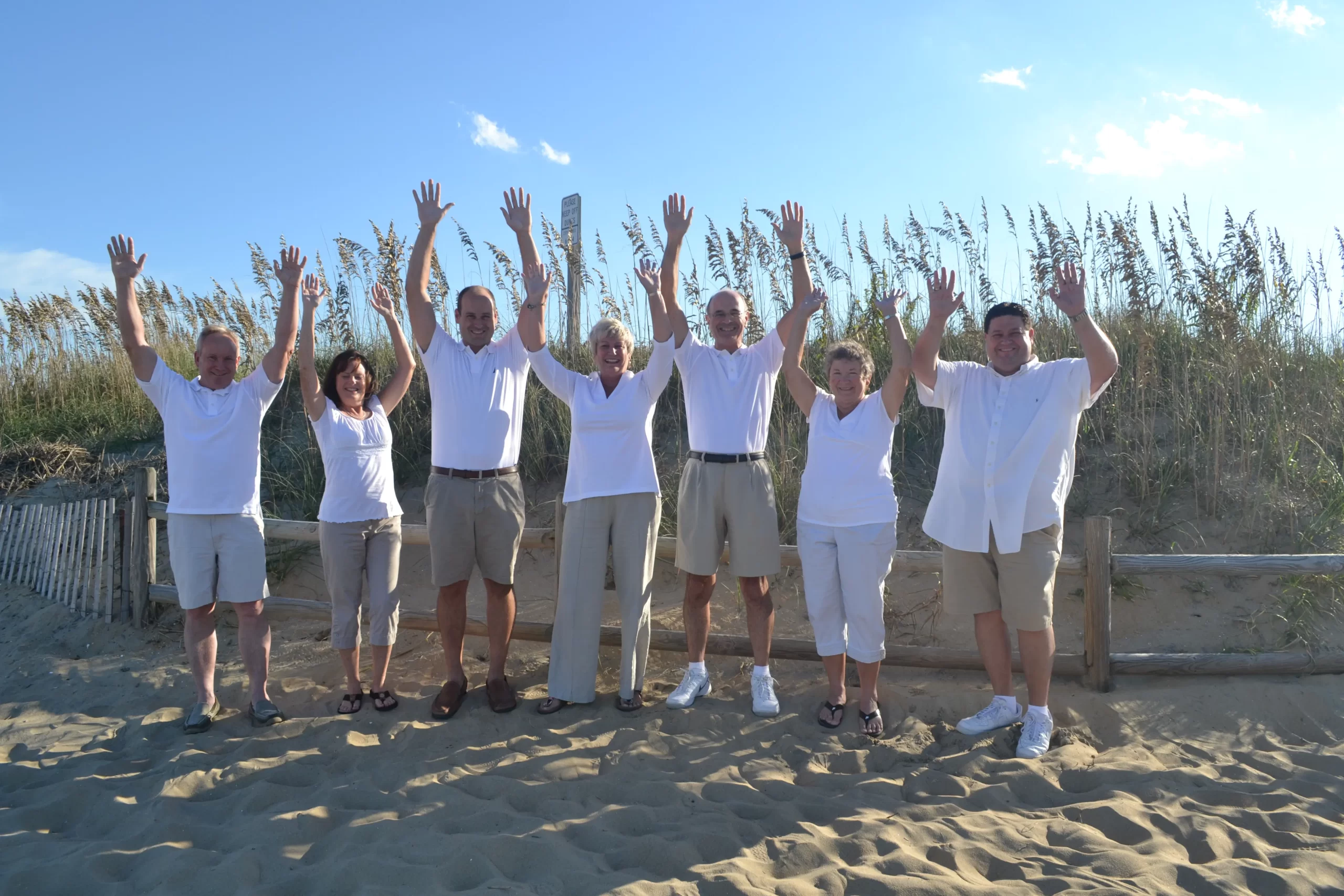 DSC_4095 people in white shirts standing in a line with arms raised, enjoying a beach day - Siebert Realty Sales